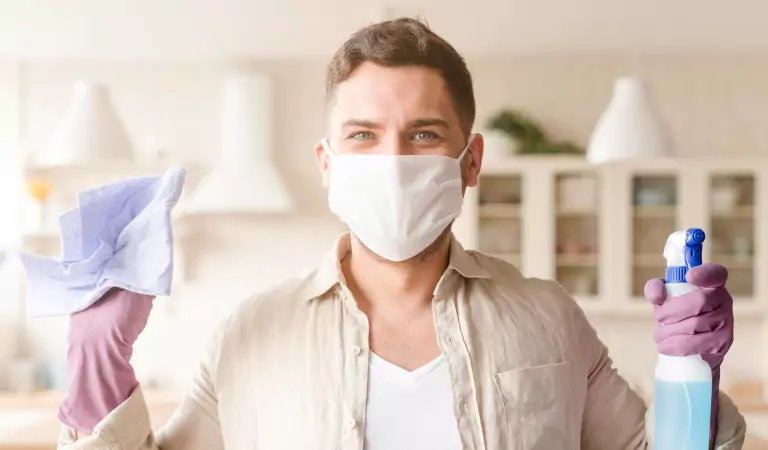young man wearing a mask with some cleaning essentials