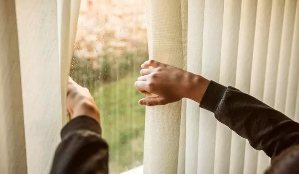 person opening window blinds