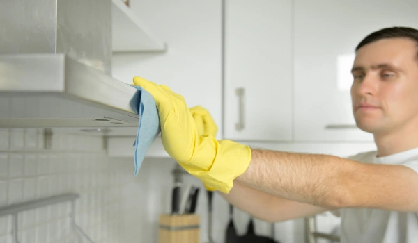 Closeup of male hands in rubber gloves cleaning extractor hood