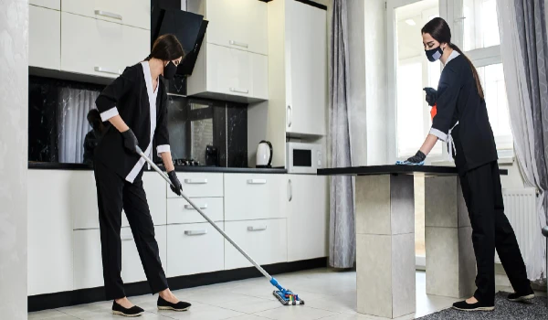 Professional cleaners in rubber gloves with a mop removes dirt from the floor and kitchen