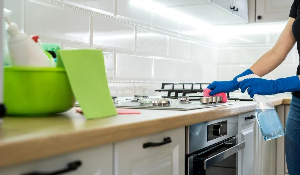 Young woman cleaning in rubber gloves and sponge in the kitchen at home