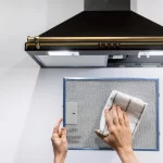 Woman washing cooker hood filter at kitchen