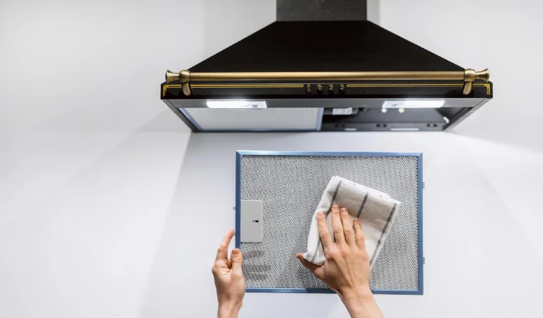 Woman washing cooker hood filter at kitchen