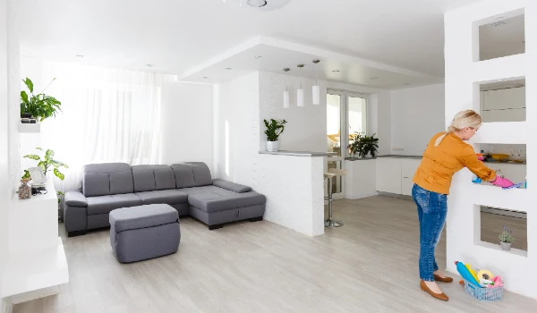 A woman cleaning furniture in kitchen with a rag