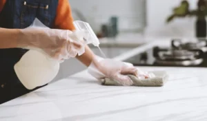 A person wearing gloves when cleaning counter with disinfectant spray