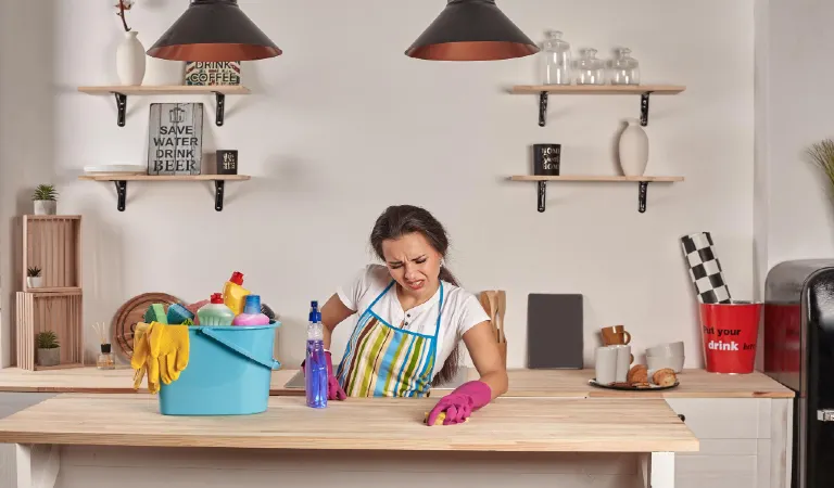 Beautiful cheerful brunette woman in gloves cleaning modern kitchen