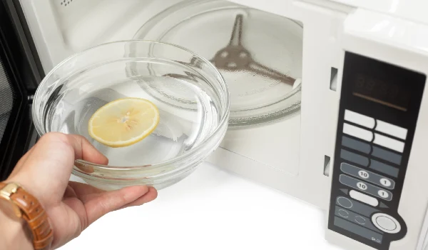 lemon and water in a bowl putting in a microwave