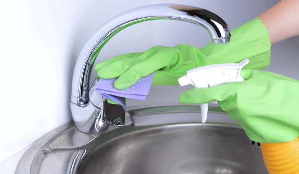 Cleaning kitchen sink chrome tap closeup